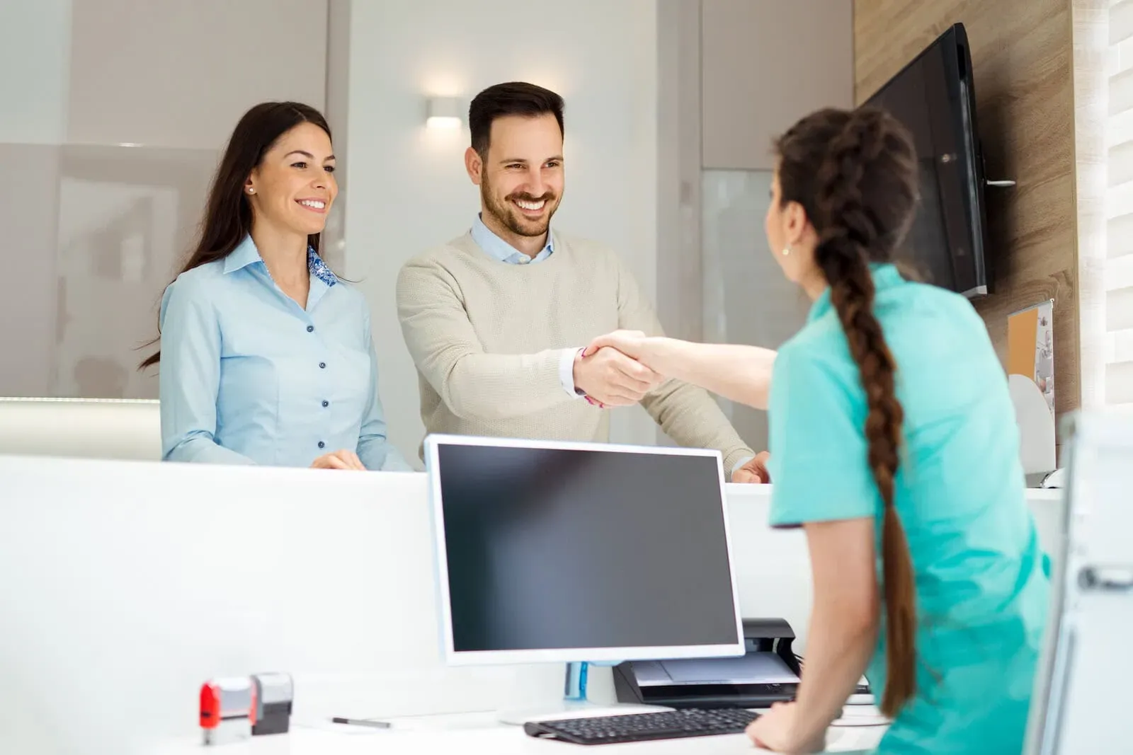 Patient shaking hands with a team member at the front desk